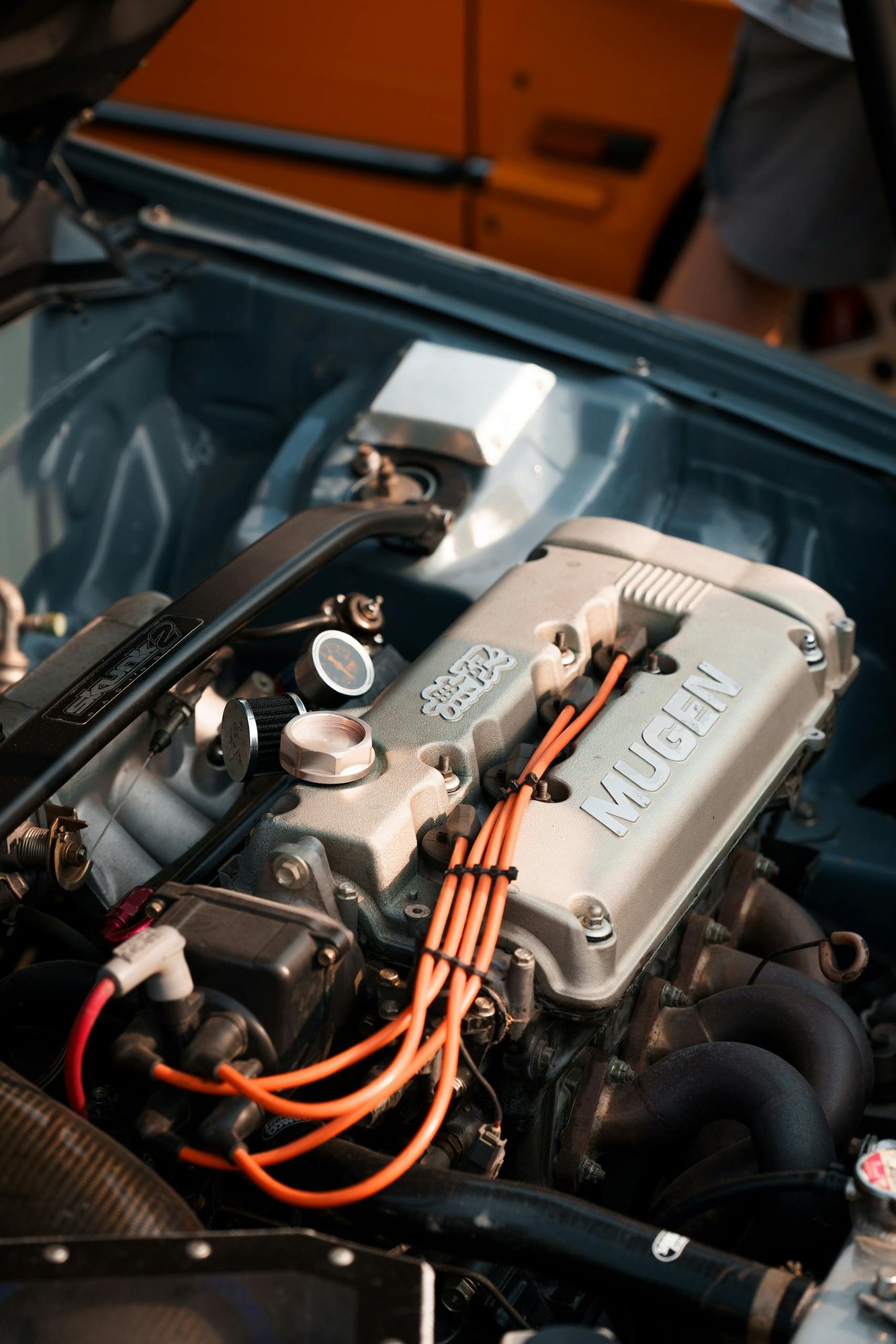 Detailed view of a modified car engine featuring a Mugen valve cover, ideal for automotive enthusiasts.